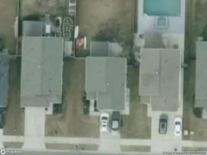Aerial view of residential houses with driveways and a swimming pool in the backyard.
