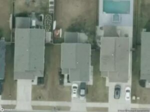 Aerial view of residential houses with driveways and a swimming pool in the backyard.