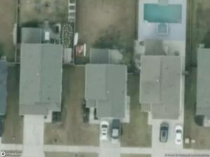 Aerial view of several houses with driveways and a pool in the backyard.