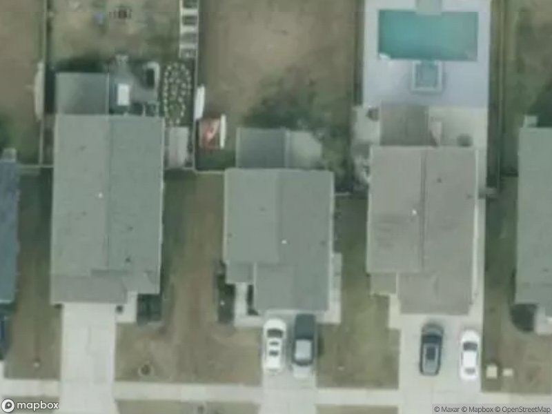 Aerial view of several houses with driveways and a pool in the backyard.