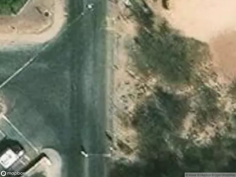 Aerial view of a road intersection with surrounding vegetation and sandy areas.