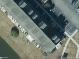 Aerial view of residential buildings near a parking lot and a small body of water.