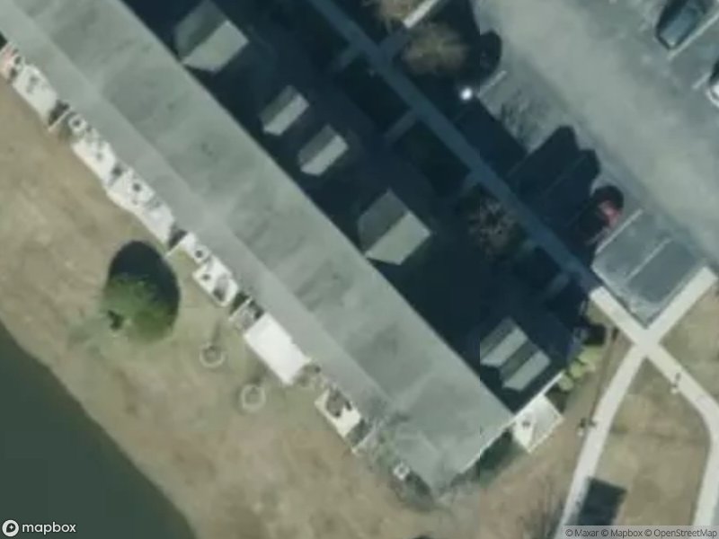 Aerial view of residential buildings, parking lot, and a small pond.