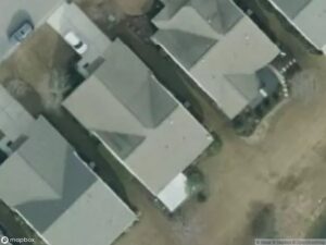 Aerial view of several residential houses with gray roofs and surrounding yards.