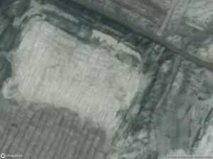 Aerial view of a rectangular cleared area surrounded by uneven terrain and roads.