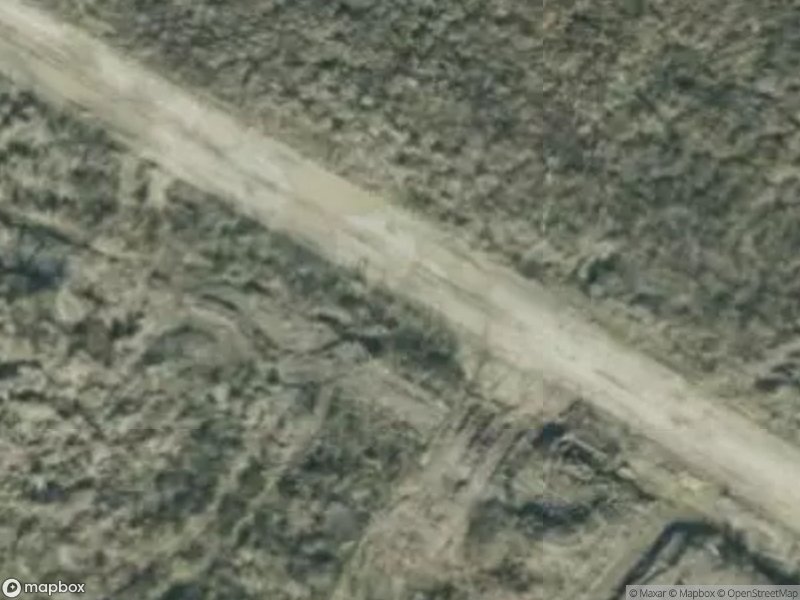 Aerial view of a dirt road surrounded by dense vegetation and uneven terrain.