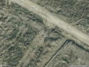 Aerial view of a dirt road intersecting uneven terrain with sparse vegetation.