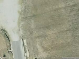 Aerial view of a gravel road intersecting a barren field.
