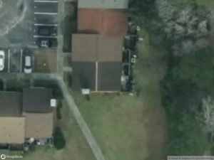 Aerial view of residential area with houses, parking spaces, and green space.
