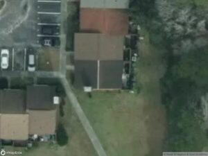 Aerial view of residential area with houses, parking spaces, and green space.