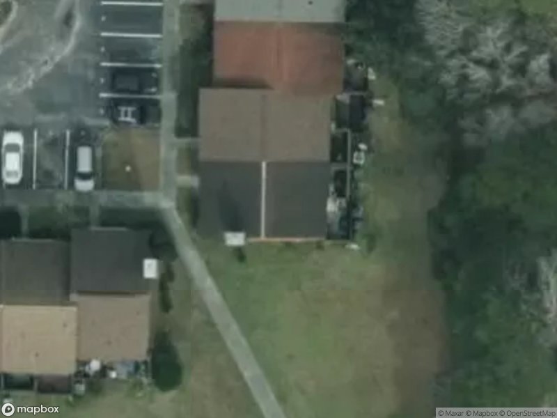 Aerial view of residential area with houses, parking spaces, and green space.