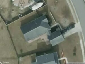 Aerial view of residential buildings, driveways, and surrounding landscape.