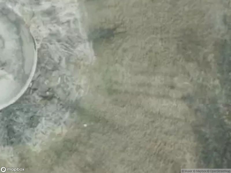 Aerial view of a circular structure surrounded by water and sandy terrain.