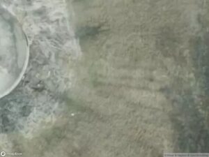 Aerial view of land with varying textures and colors, possibly water and vegetation.