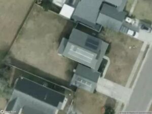 Aerial view of residential area with houses and driveways, showing grassy yards.