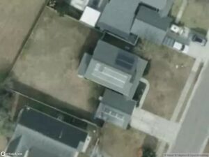Aerial view of residential houses with solar panels and surrounding lawns.