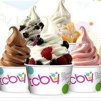 Five cups of soft-serve frozen yogurt in various flavors, topped with fruits and cookies.