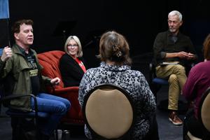 A group of people engage in discussion, with one man speaking and three others listening attentively.