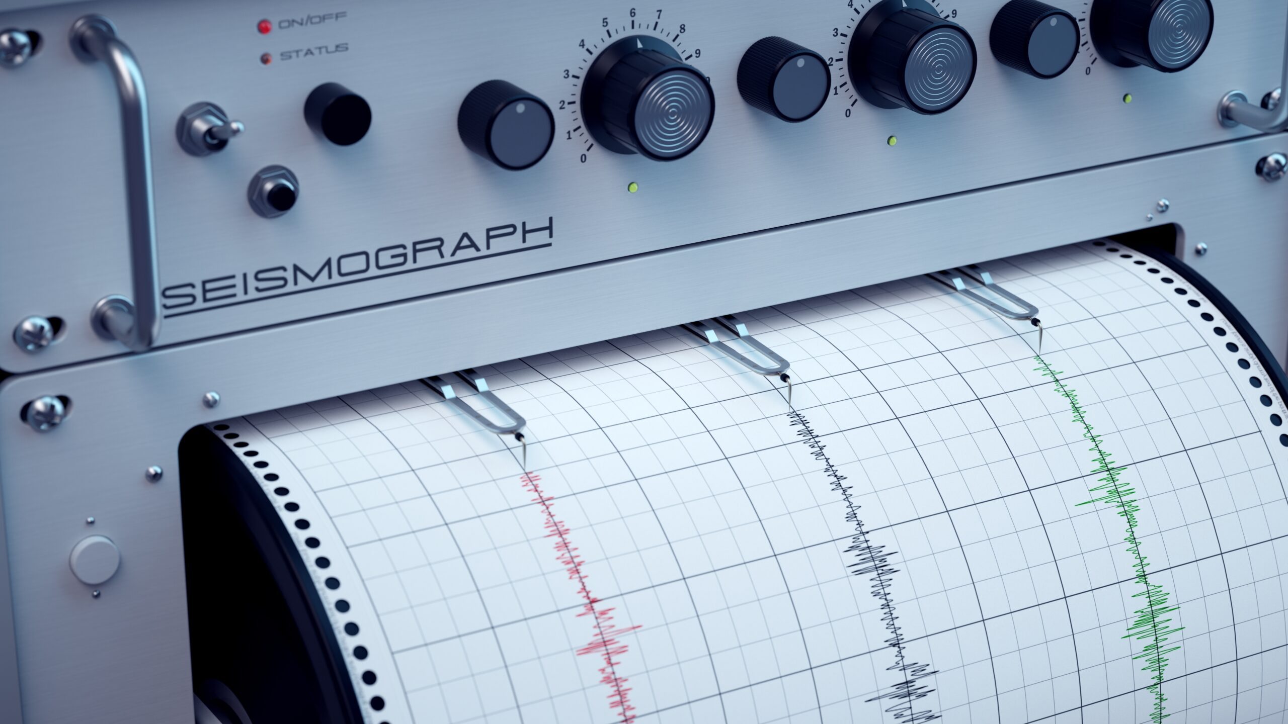 A seismograph displays recorded seismic waves on graph paper, showing red and green lines.