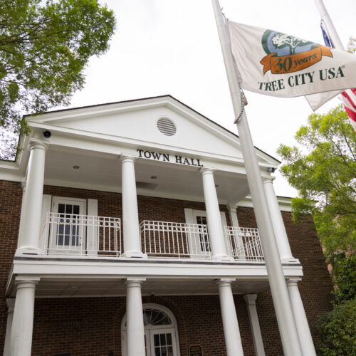 Summerville Town Hall features white columns, city and American flags, surrounded by greenery.