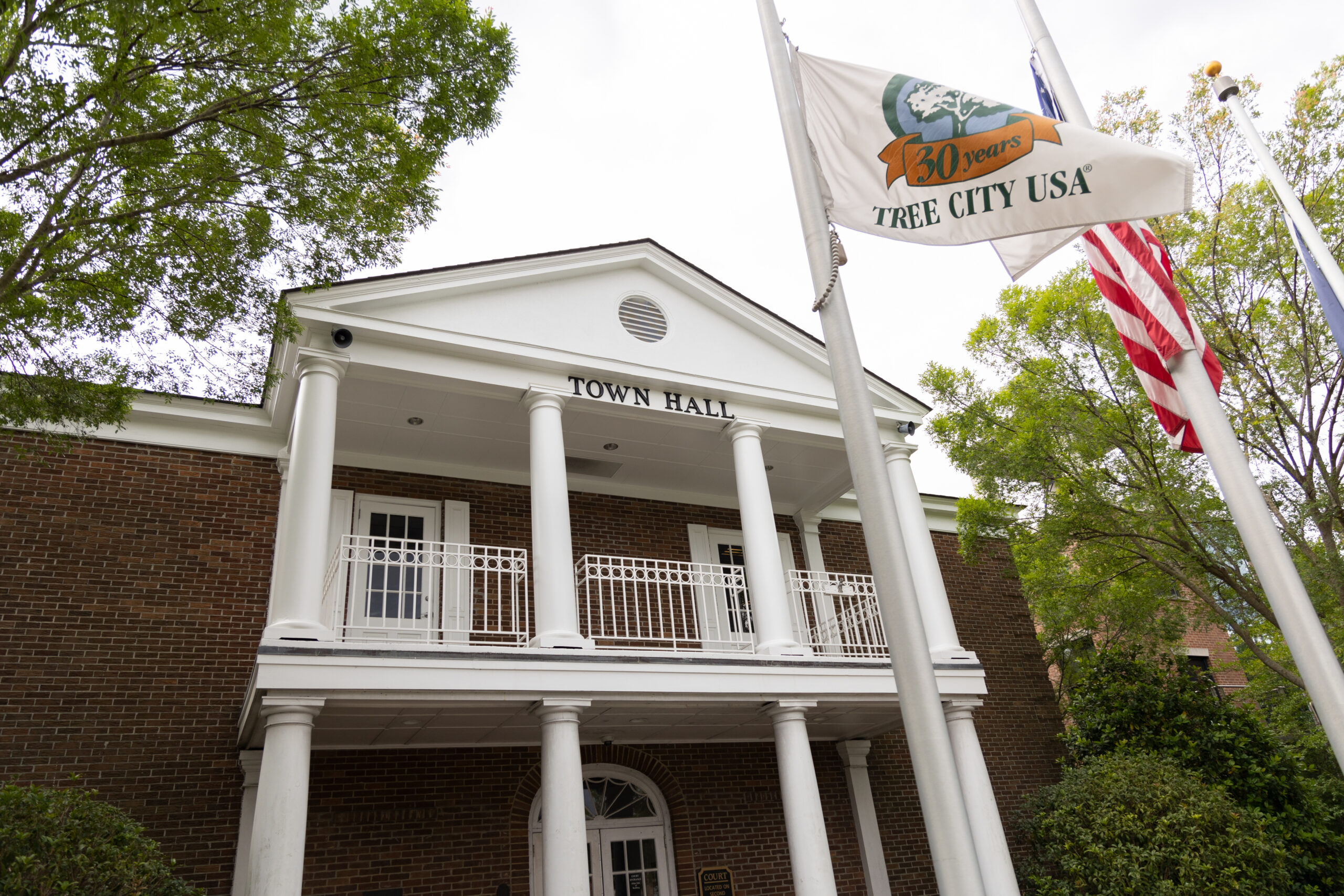Summerville Town Hall features white columns, city and American flags, surrounded by greenery.