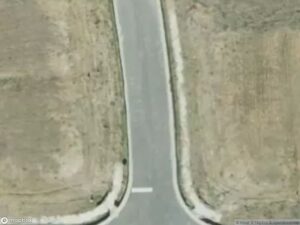 Aerial view of a road curving between two barren areas.