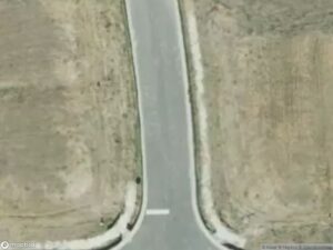 Aerial view of a road intersecting with bare land on both sides.