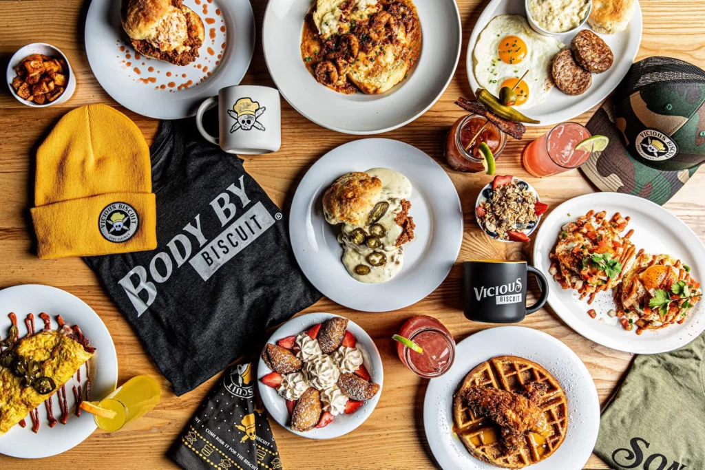 A variety of breakfast dishes, drinks, and merchandise on a wooden table.