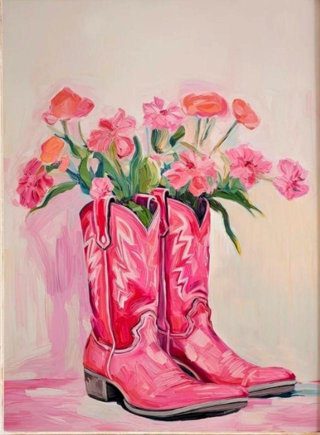 Pink cowboy boots filled with colorful flowers against a light background.