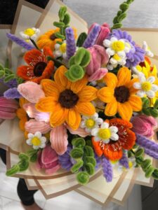 A vibrant bouquet of colorful pipe cleaner flowers, including sunflowers, tulips, and daisies.