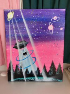 A colorful painting of a UFO beaming up a cow over a forest, with planets and stars in the background.