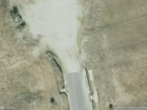 Aerial view of a road leading to a gravel area, surrounded by dry grass.