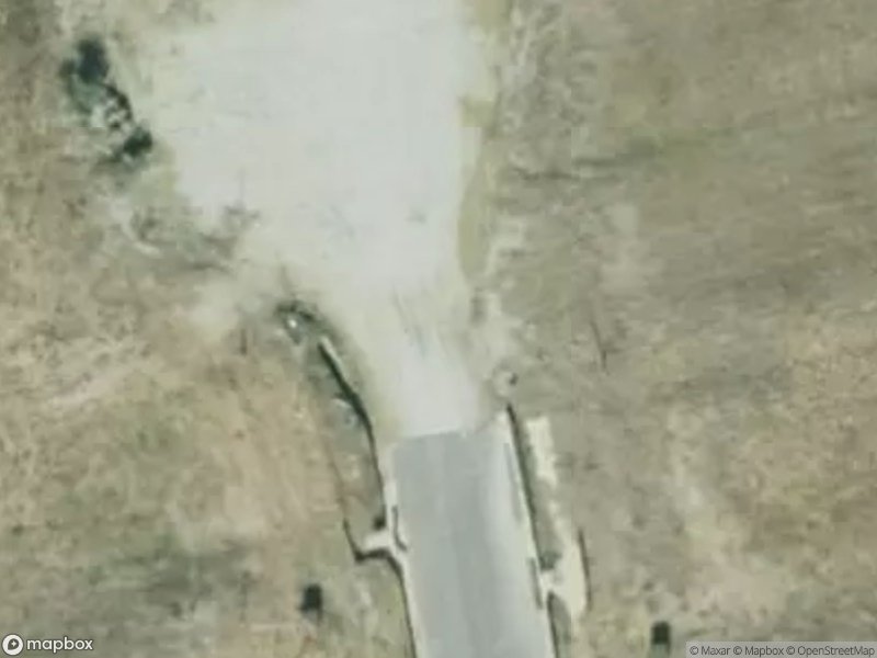 Aerial view of a road leading to a gravel area, surrounded by dry grass.