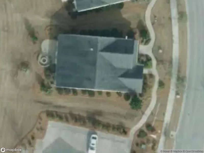 Aerial view of a house with a driveway and landscaped yard. Surrounding roads are visible.