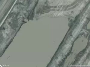 Aerial view of a gray landscape with water and dirt paths.