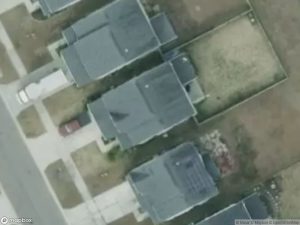 Aerial view of several houses with driveways and grassy areas.