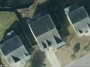 Aerial view of several residential houses with triangular roofs and surrounding greenery.
