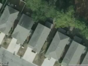 Aerial view of residential houses with gray roofs and surrounding trees.