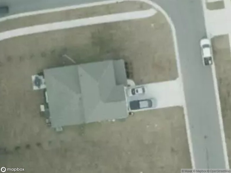 Aerial view of a house with a driveway and two parked cars on a residential street.