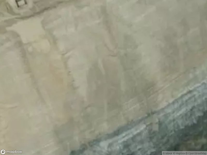 Aerial view of a rocky terrain with layered earth and water at the bottom.