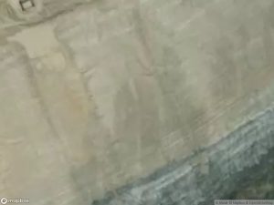 Aerial view of a sandy terrain with visible geological features and a water edge.