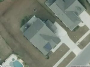 Aerial view of residential homes with driveways and a pool in the backyard.