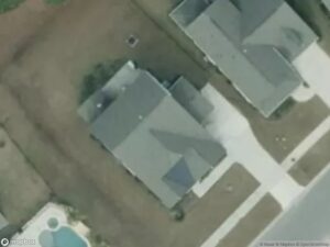 Aerial view of residential homes with driveways and a pool in the backyard.