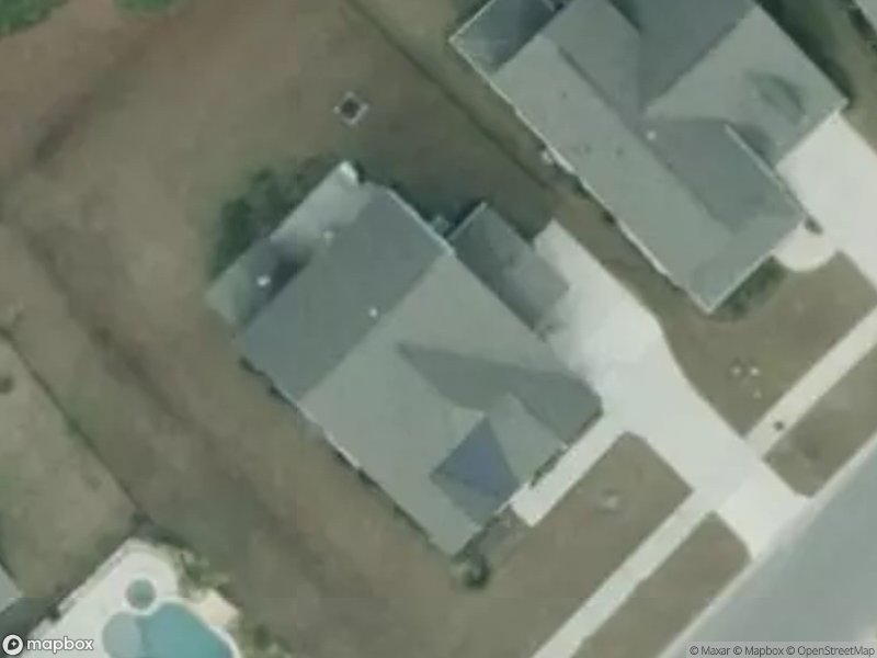 Aerial view of residential homes with driveways and a pool in the backyard.