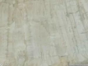 Satellite image showing a textured, light-colored terrain with subtle variations in surface patterns.