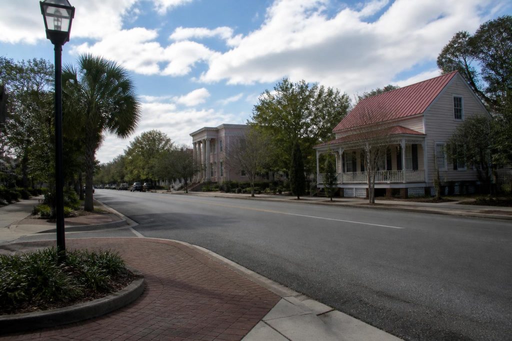 Quiet street in Summerville, SC, lined with trees and historic homes under a partly cloudy sky.